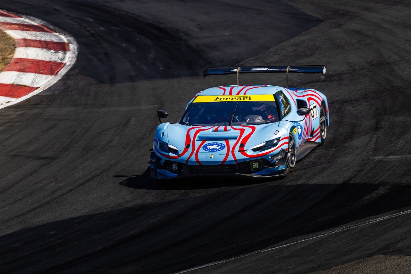 A liveried Ferrari competition car cornering on track.